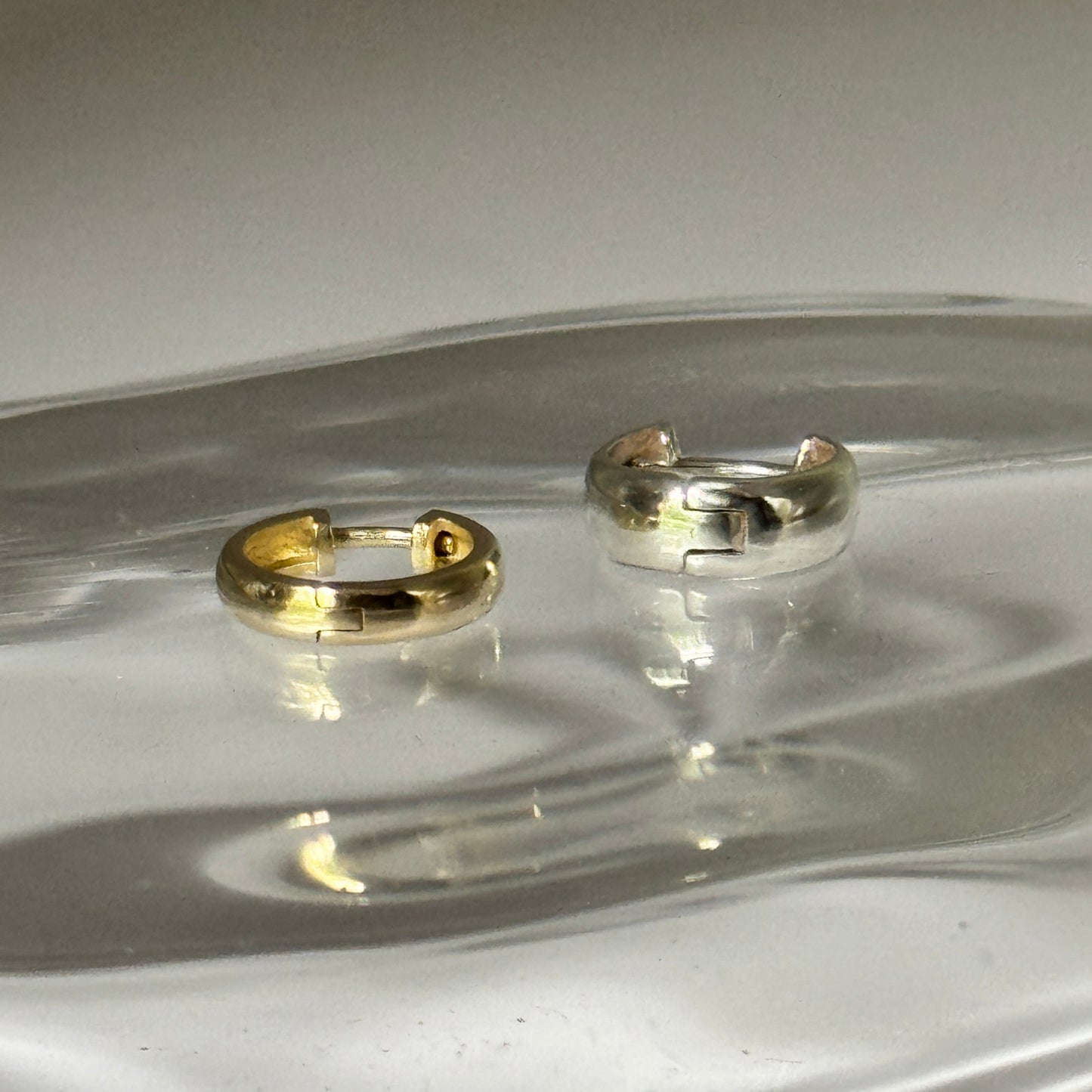 Two earrings on a clear glass surface with a white background