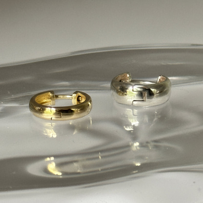 Two earrings on a clear glass surface with a white background
