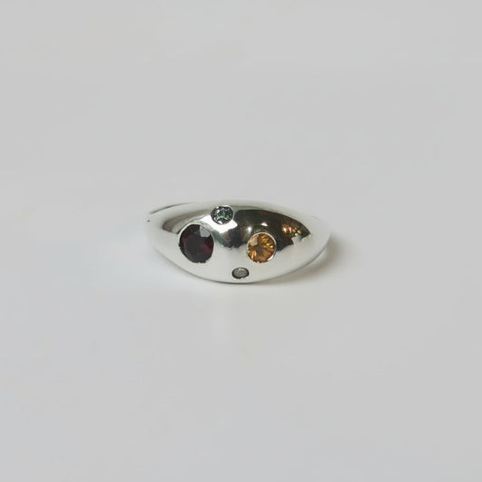 Silver ring with embedded gemstones on a light gray background