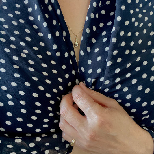 Close-up of a person wearing a navy blue polka dot garment with a hand adjusting it.