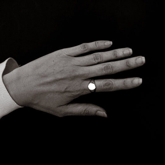 Hand wearing a ring on a black background