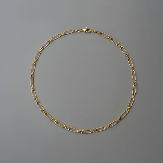 Gold chain necklace on a gray background