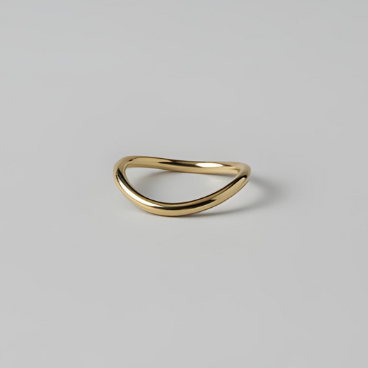 Gold ring with a curved design on a light grey background