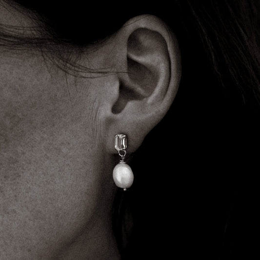 Pearl earring worn by a person against a dark background