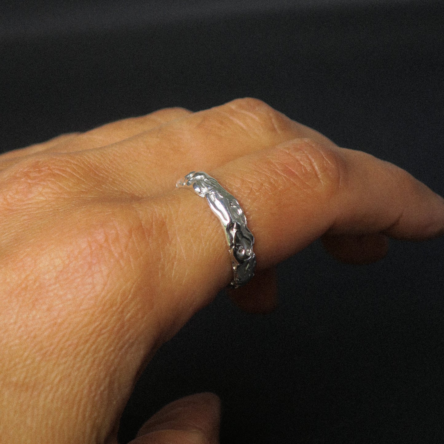 Silver ring on a person's finger against a black background
