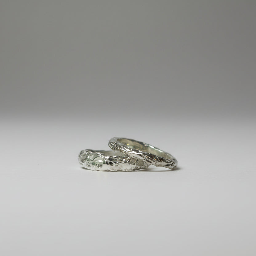 Two silver rings on a gray background