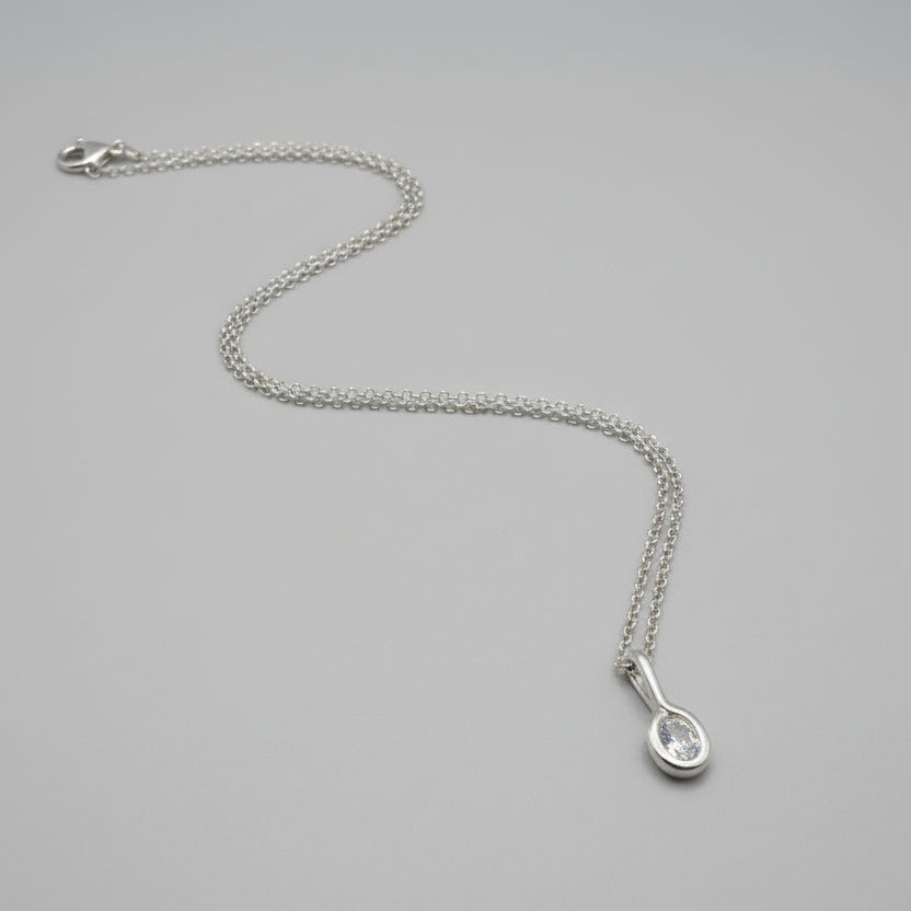 Silver necklace with a teardrop-shaped pendant on a gray background