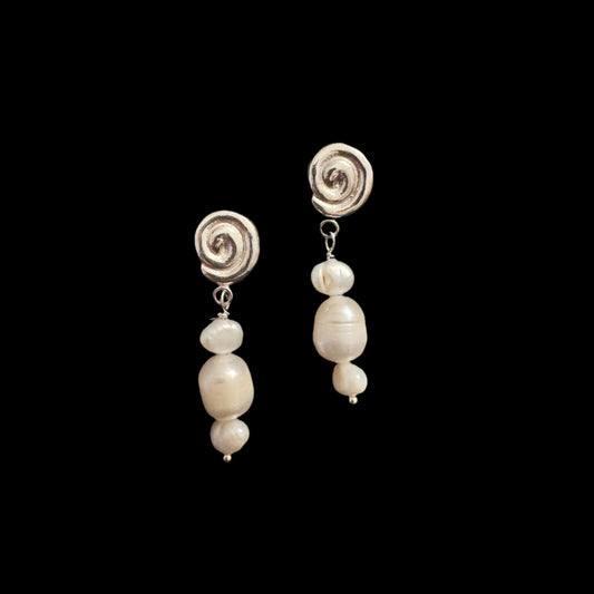 Pair of pearl earrings on a green velvet surface