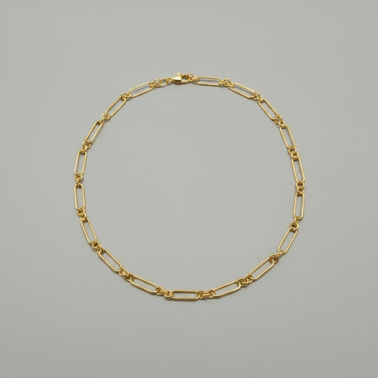 Gold chain bracelet on a gray background