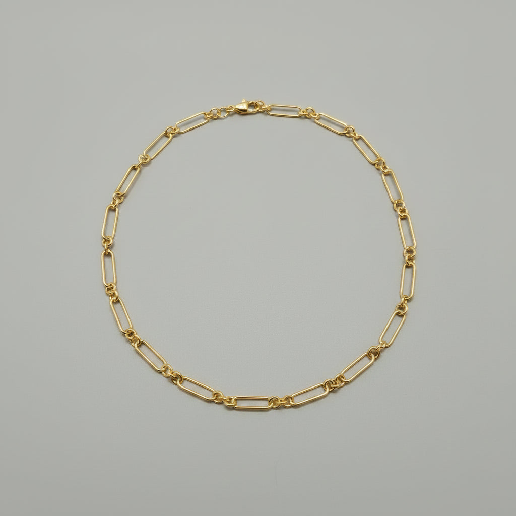 Gold chain bracelet on a gray background