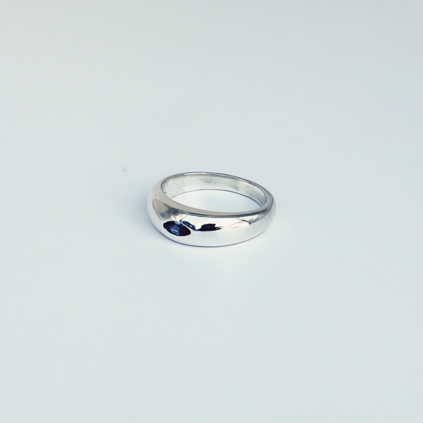 Silver ring with a blue stone on a light gray background