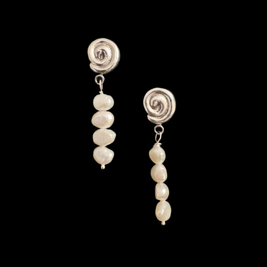 Pair of pearl earrings with silver spiral tops on a green velvet background
