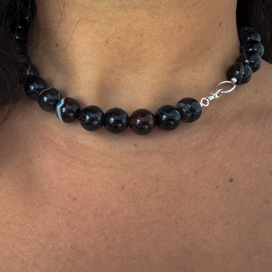 Black beaded necklace on a person's neck