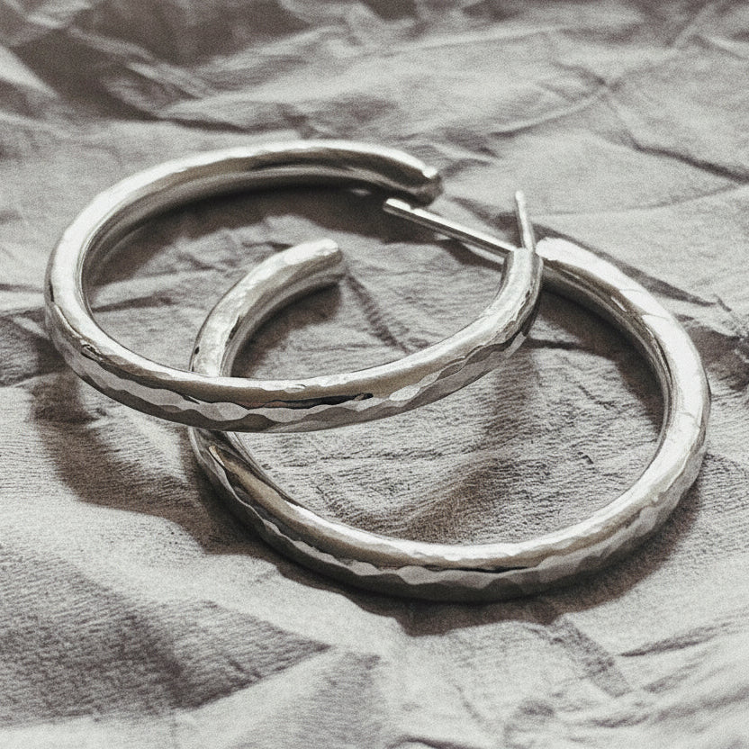 A closeup image of a pair of earrings on a crumpled white paper.