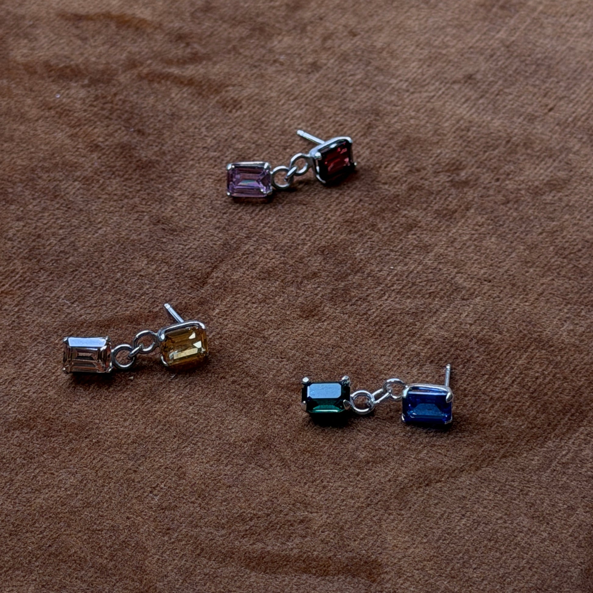 Three pairs of earrings on a brown surface