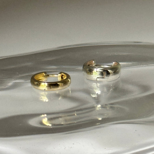 Two earrings on a clear glass surface with a white background