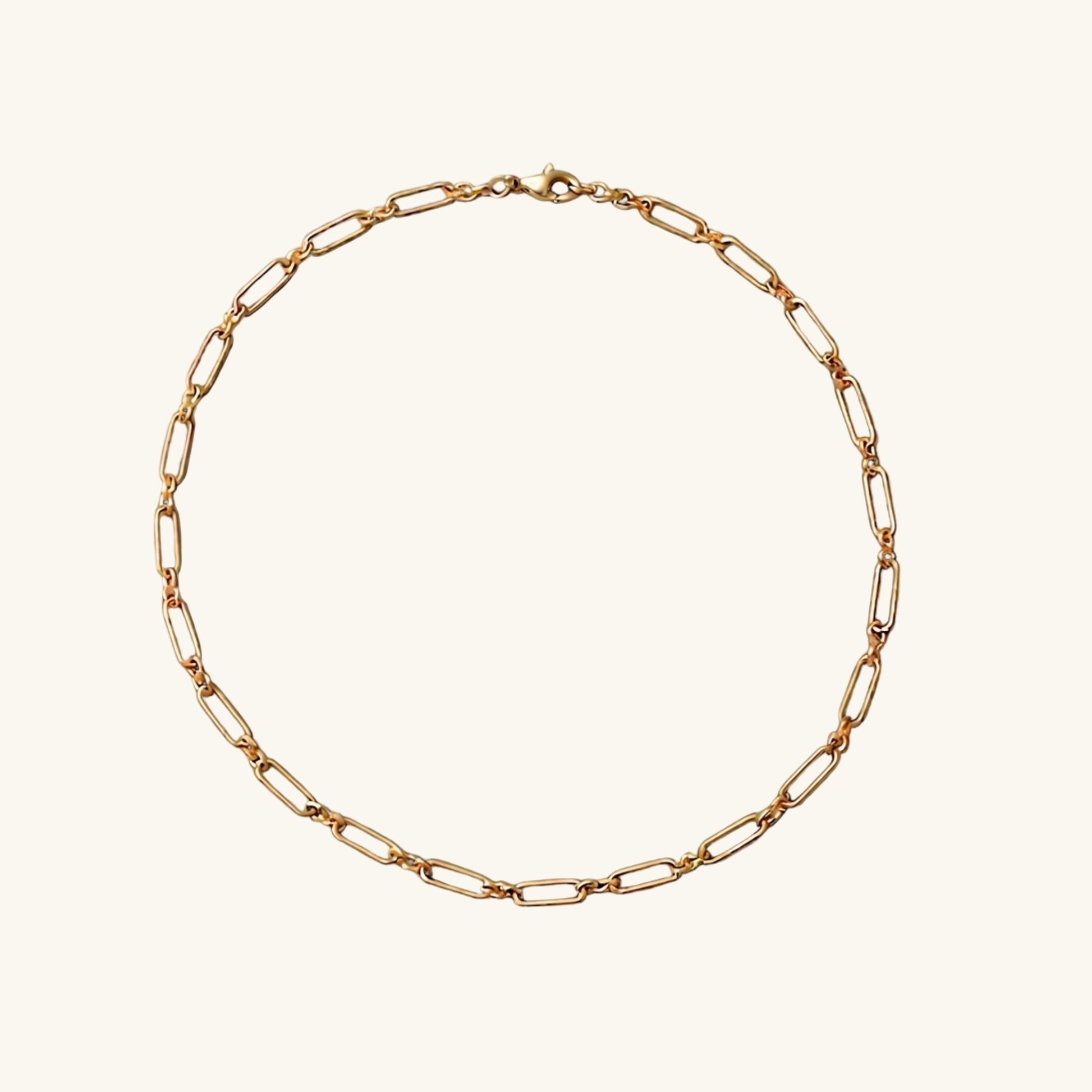 A gold paper clip chain on a white studio background