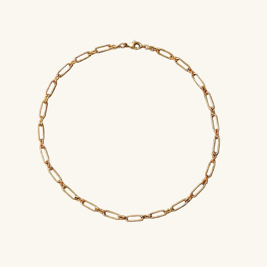 A gold paper clip chain on a white studio background