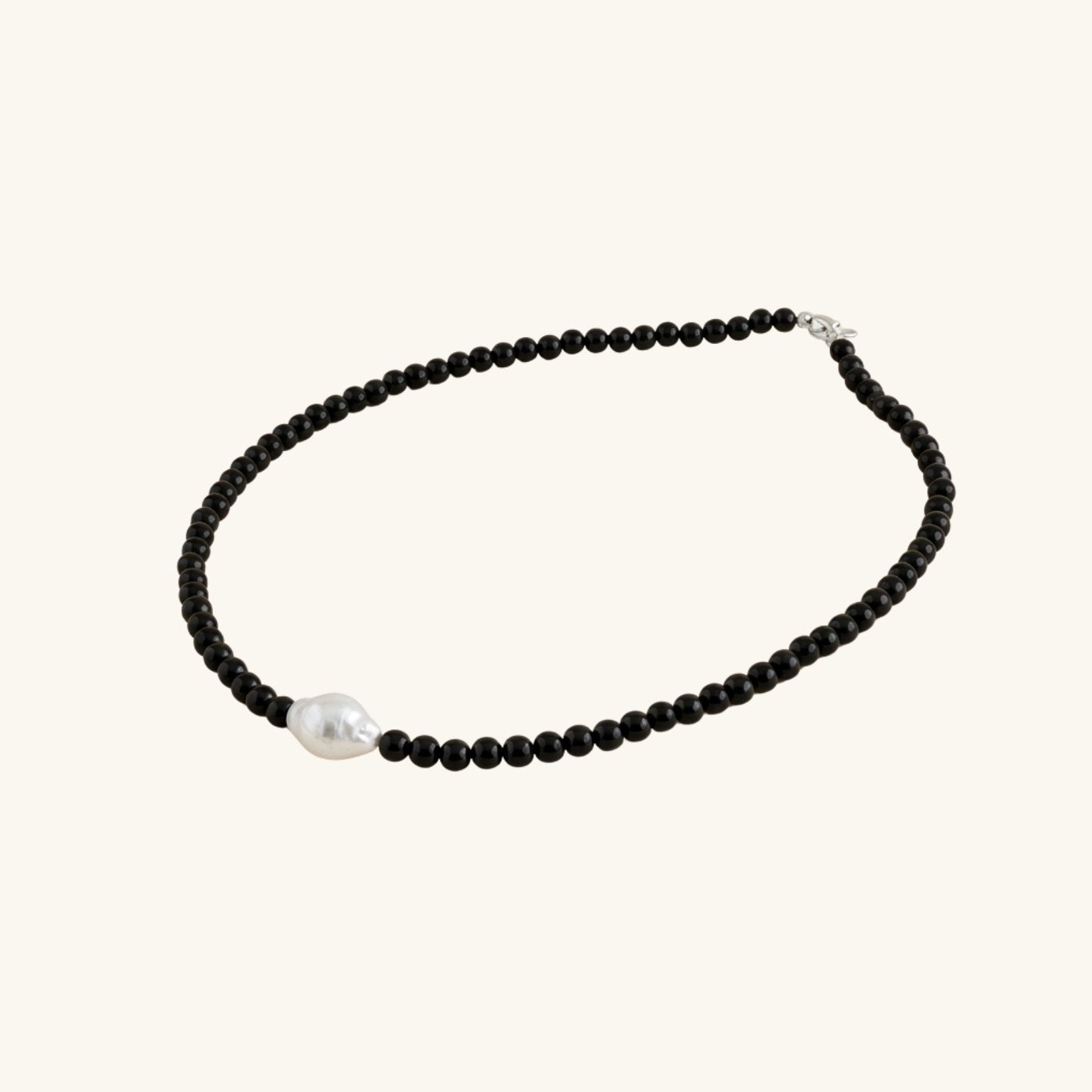 Necklace with black beads and a pearl on a white background