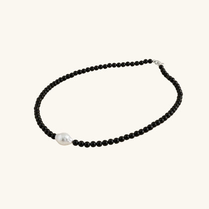 Necklace with black beads and a pearl on a white background