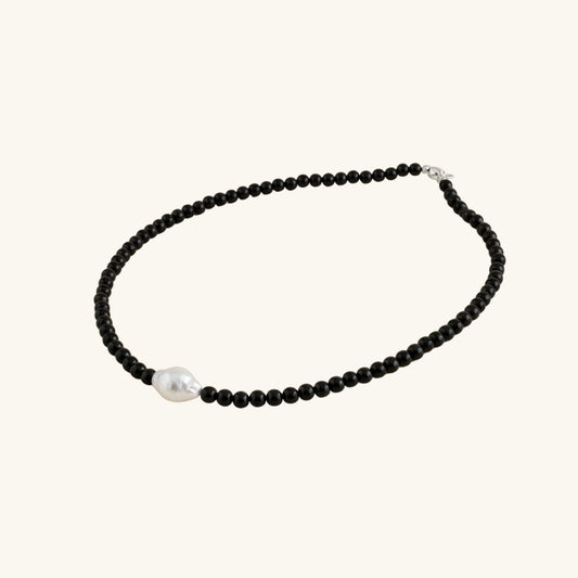 Necklace with black beads and a pearl on a white background