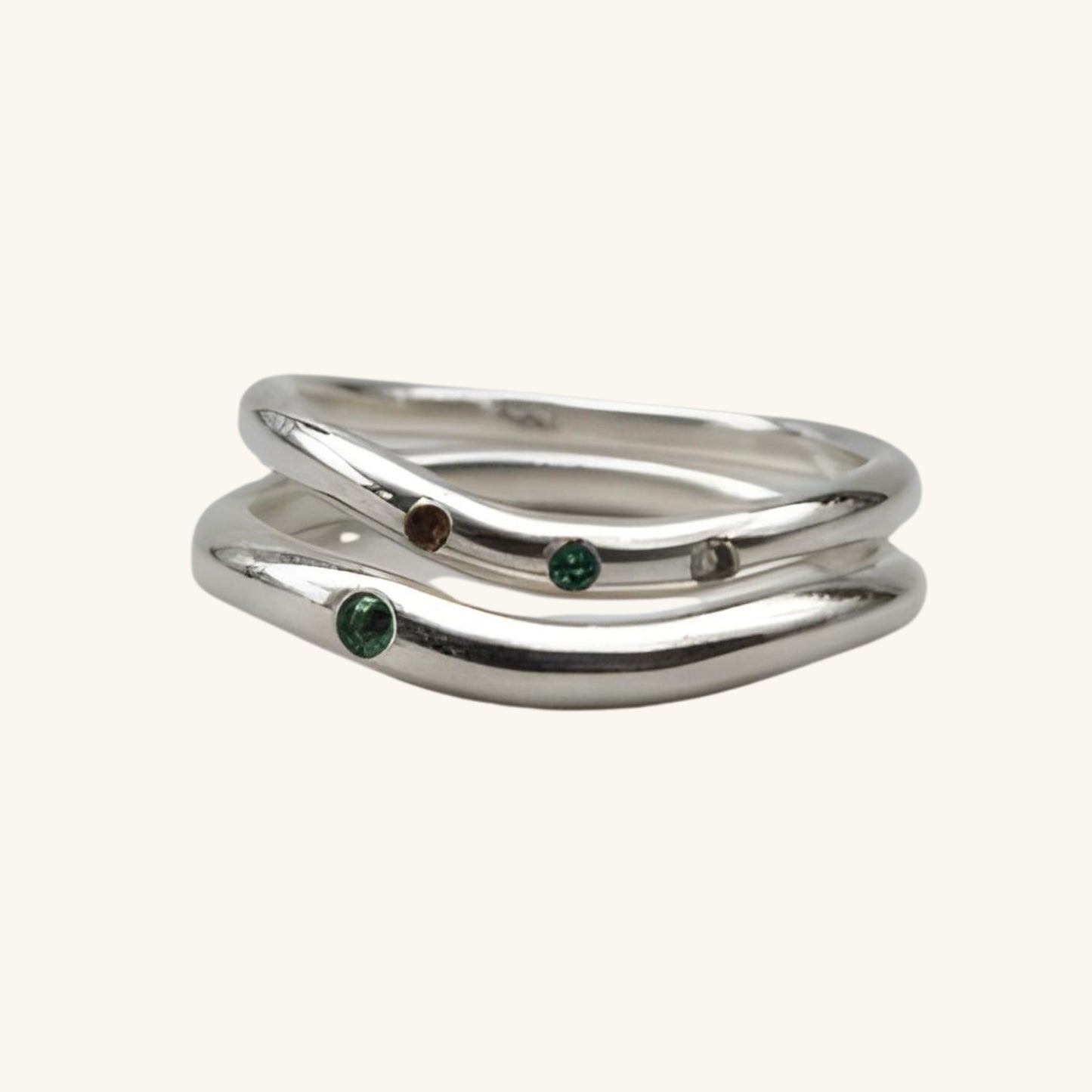 Silver ring with embedded gemstones on a beige background