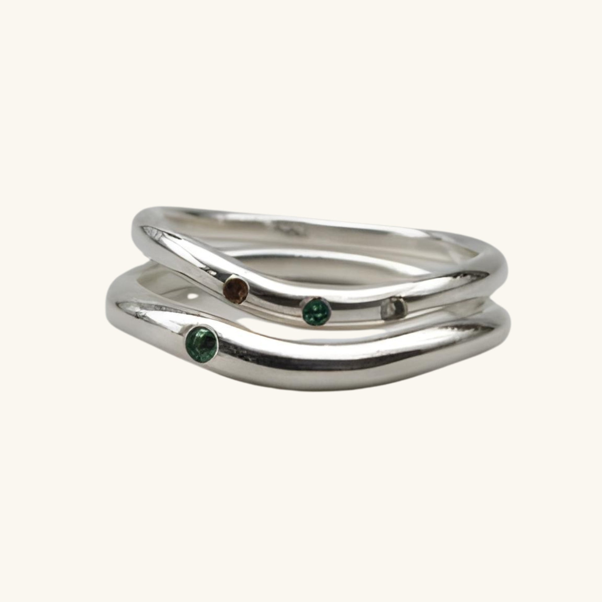 Silver ring with embedded gemstones on a beige background