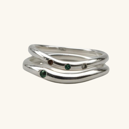 Silver ring with embedded gemstones on a beige background