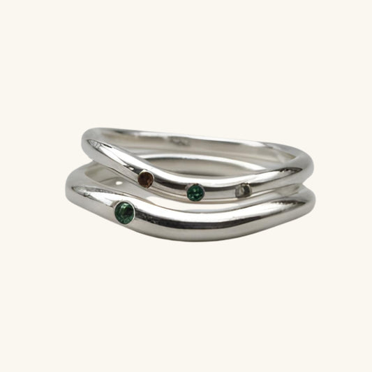 Silver ring with embedded gemstones on a beige background