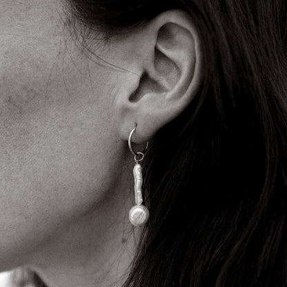 Close-up of an ear wearing a pearl earring with dark hair.