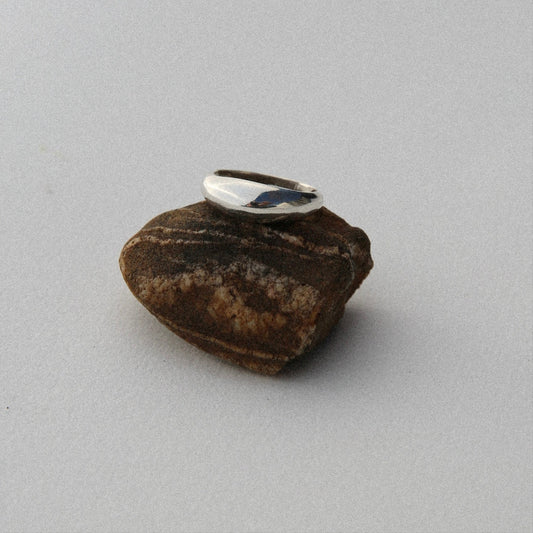 Silver ring on a brown stone against a gray background