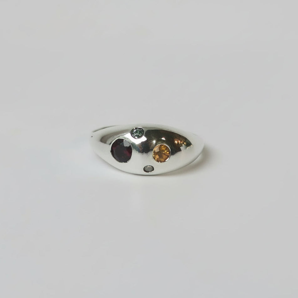 Silver ring with embedded gemstones on a light gray background