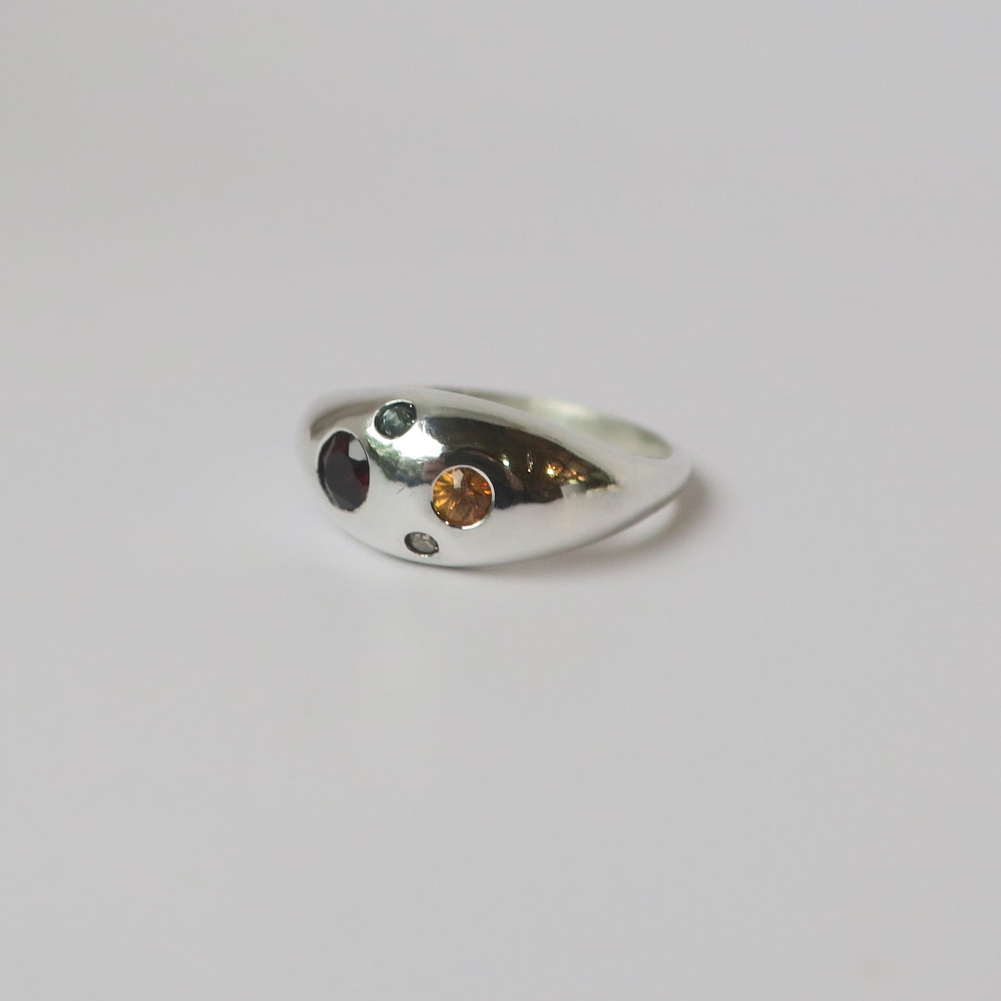 Silver ring with embedded stones on a light gray background