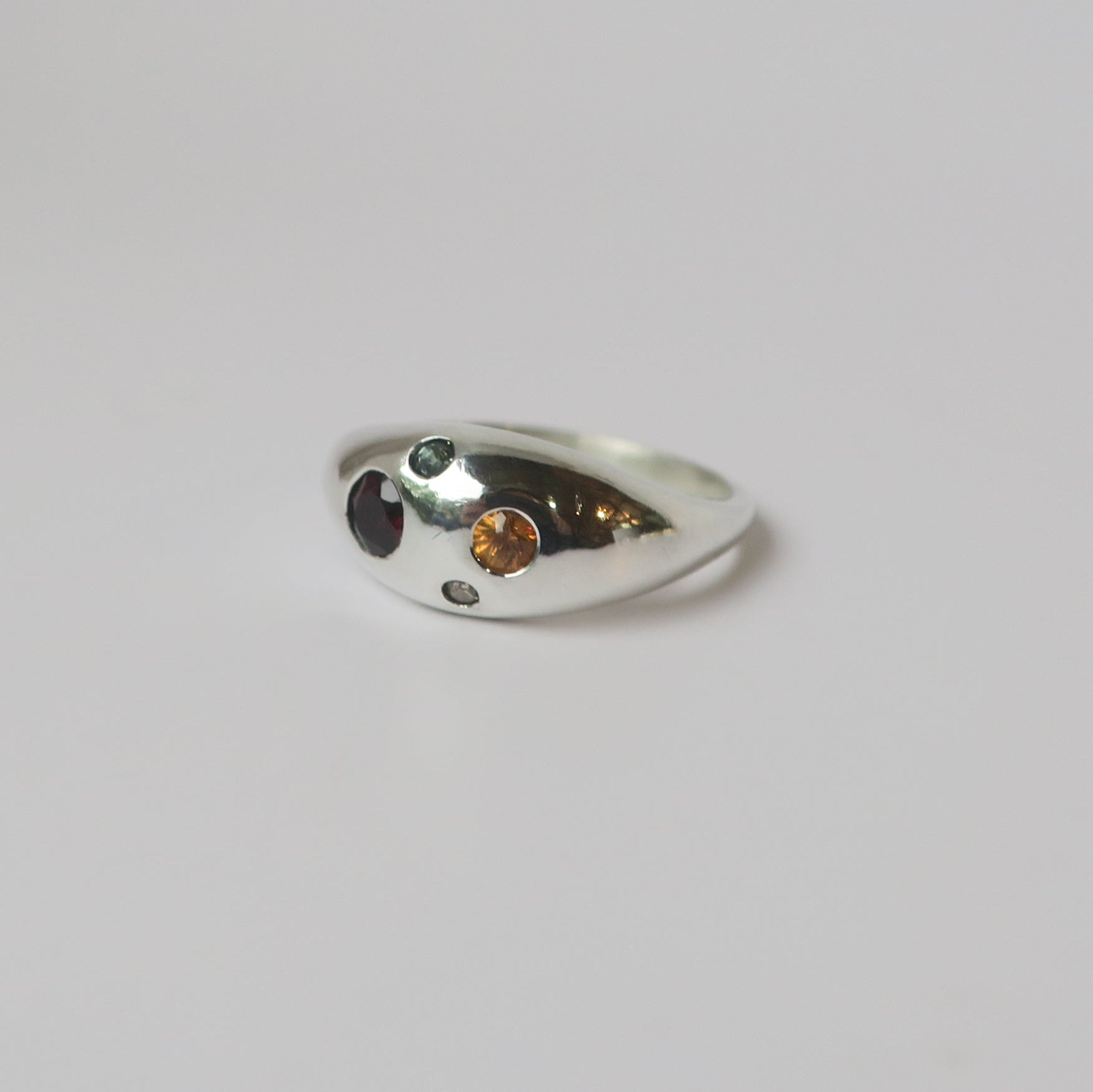Silver ring with embedded stones on a light gray background