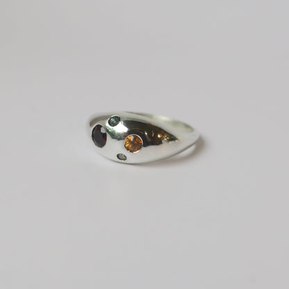 Silver ring with embedded stones on a light gray background
