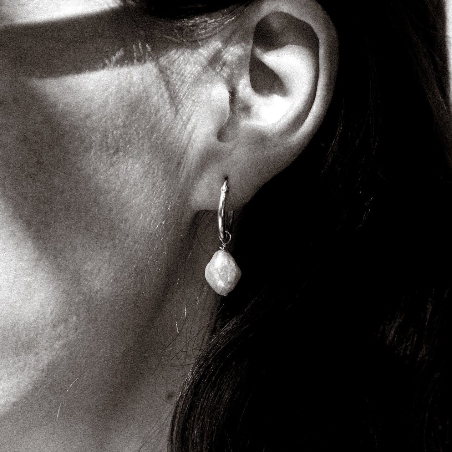 Close-up of an ear wearing a pearl earring with a blurred background