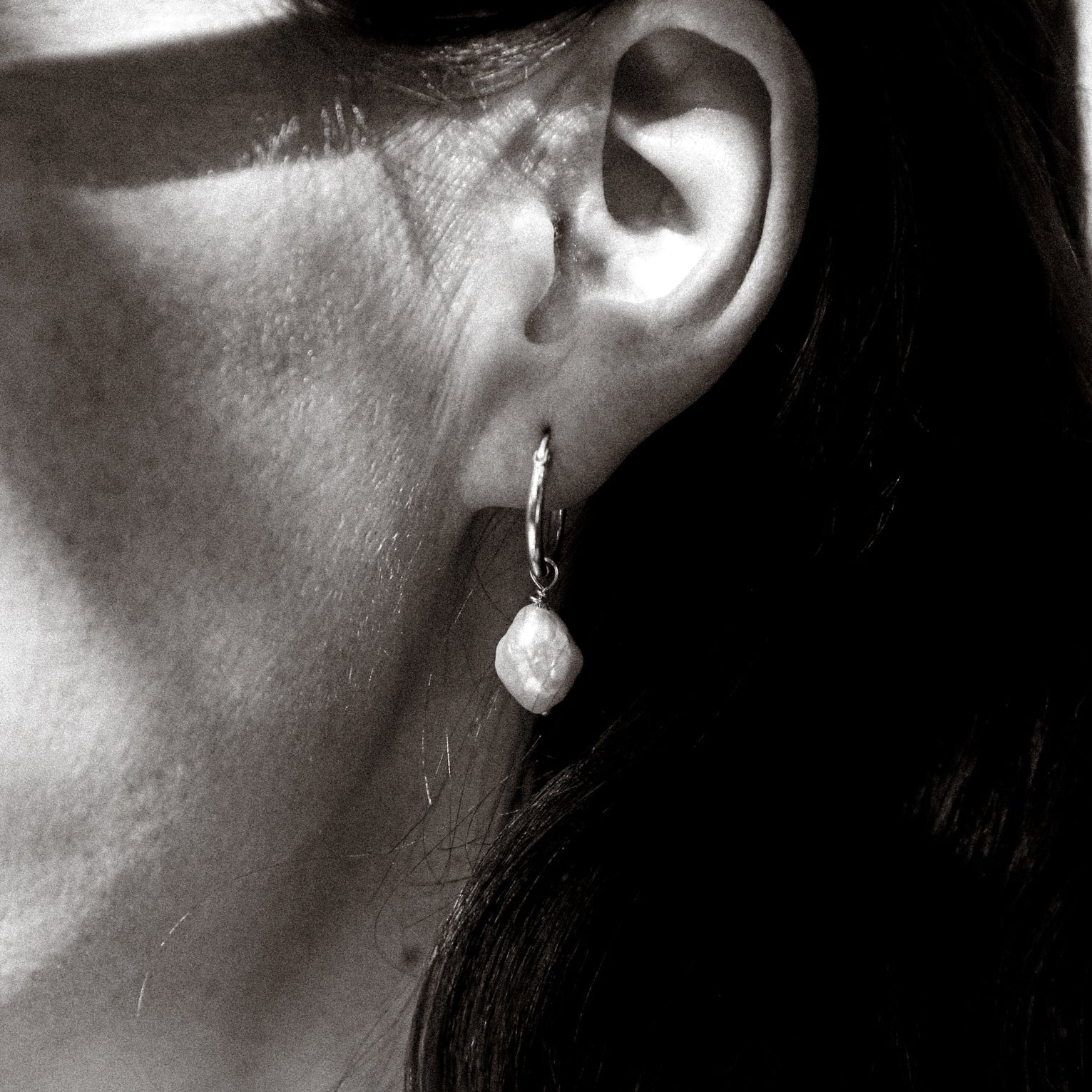 Close-up of an ear wearing a pearl earring with a blurred background