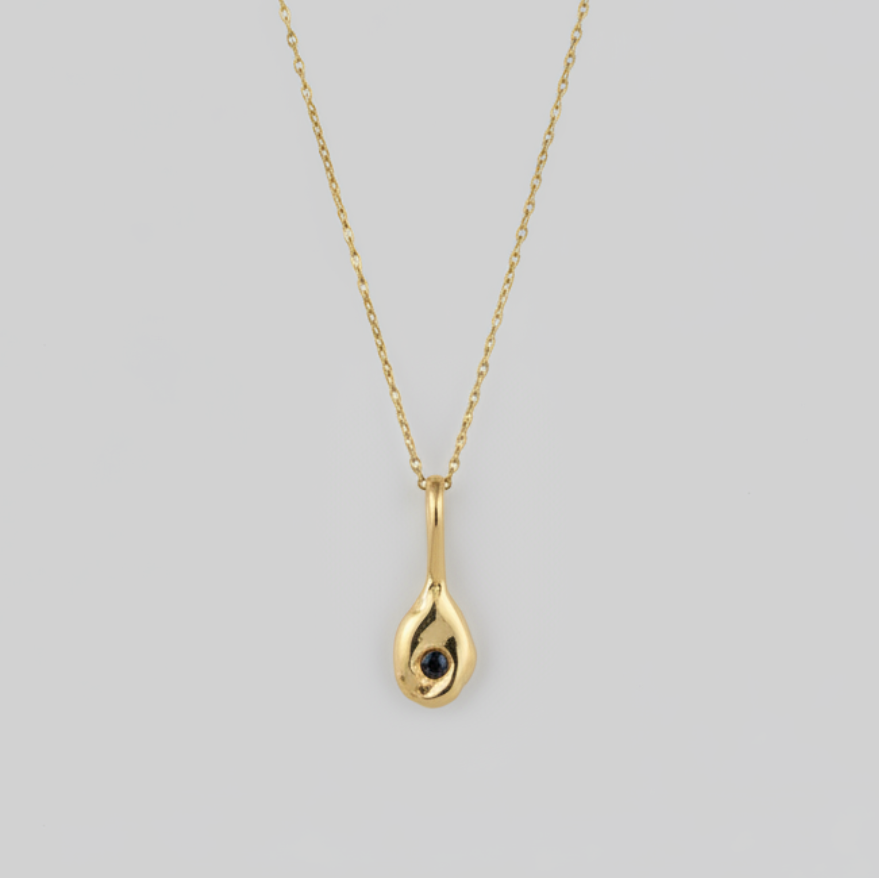 Gold necklace with a teardrop-shaped pendant on a light gray background
