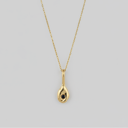 Gold necklace with a teardrop-shaped pendant on a light gray background