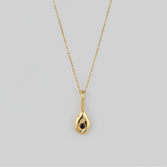 Gold necklace with a teardrop-shaped pendant on a light gray background