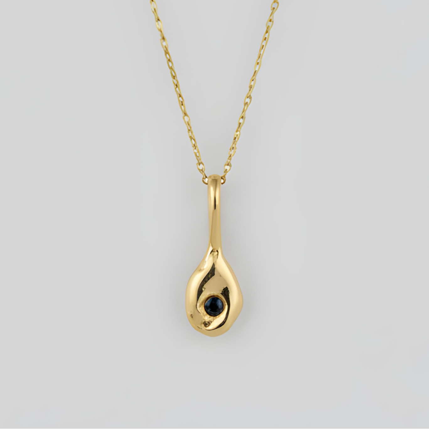 Gold teardrop pendant necklace on a light gray background