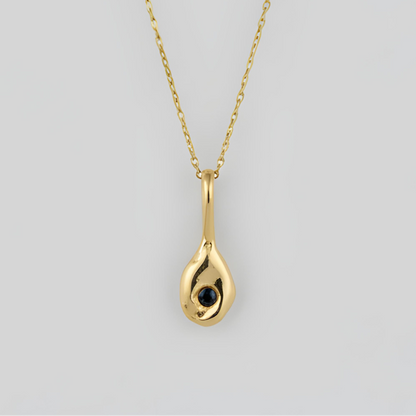 Gold teardrop pendant necklace on a light gray background