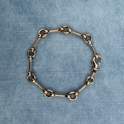 Gold chain bracelet on a textured blue fabric background