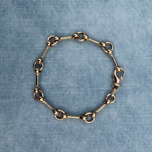 Gold chain bracelet on a textured blue fabric background