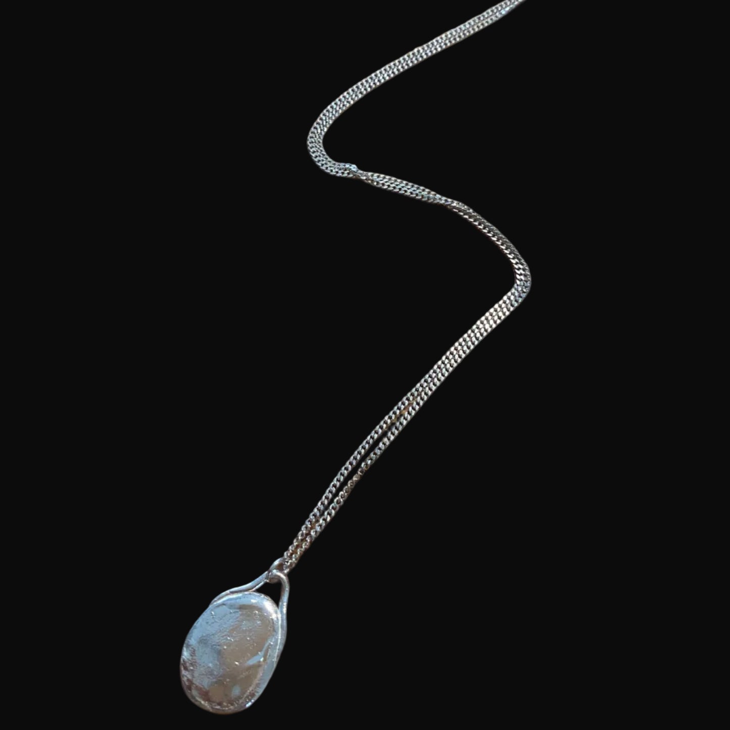 Silver necklace with a pendant on a black surface