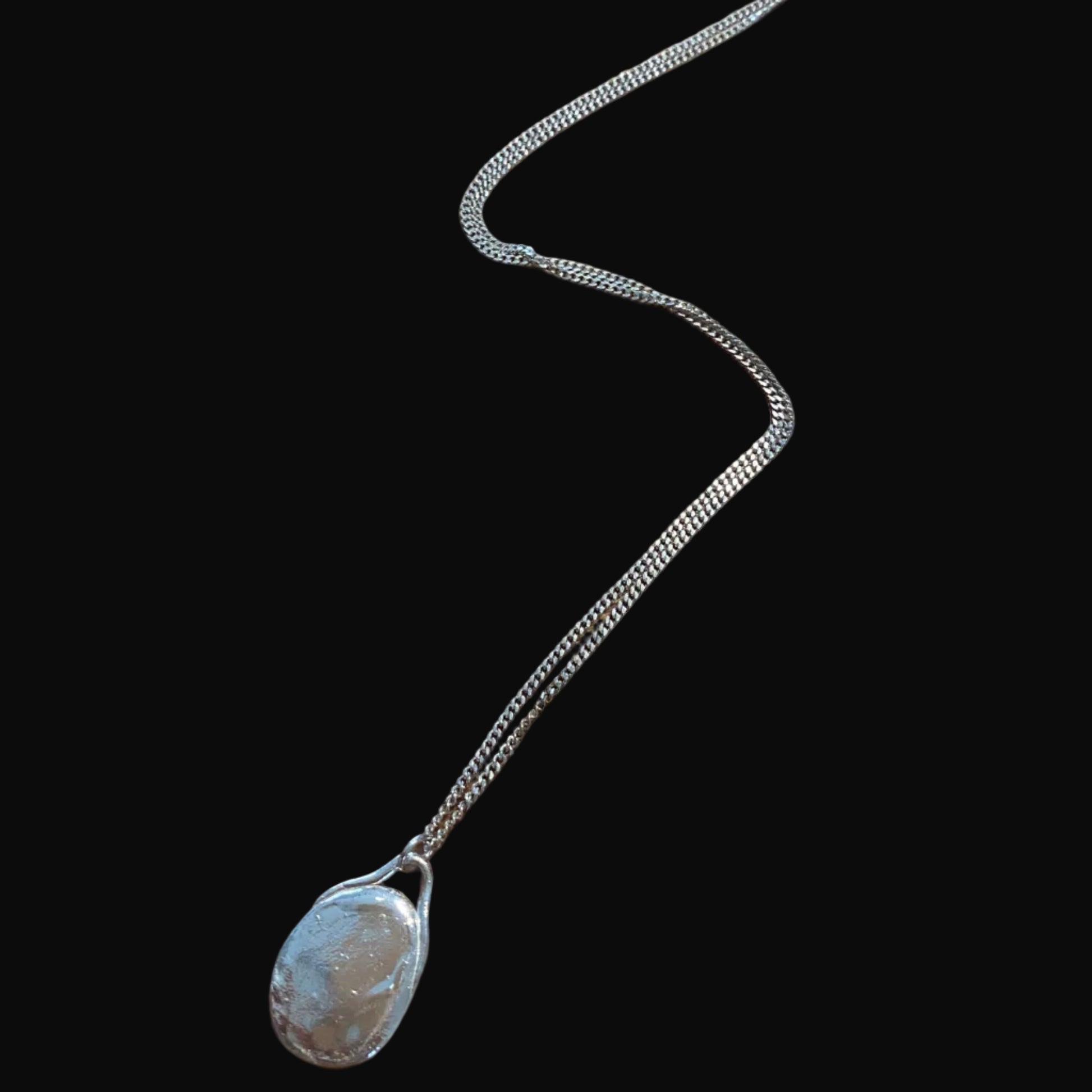 Silver necklace with a pendant on a black surface