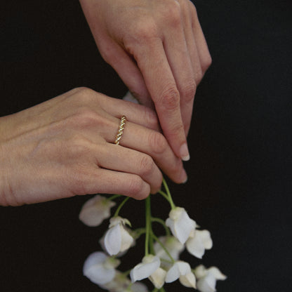Close-up of hands with a gold ring holding white flowers against a black background