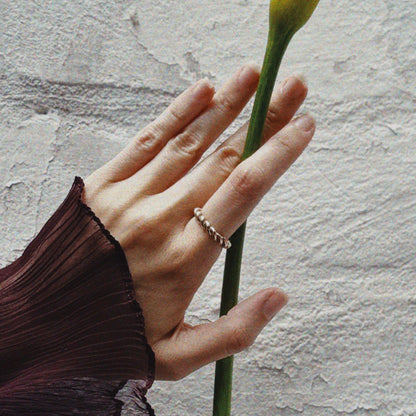 Hand holding a yellow flower against a textured wall.