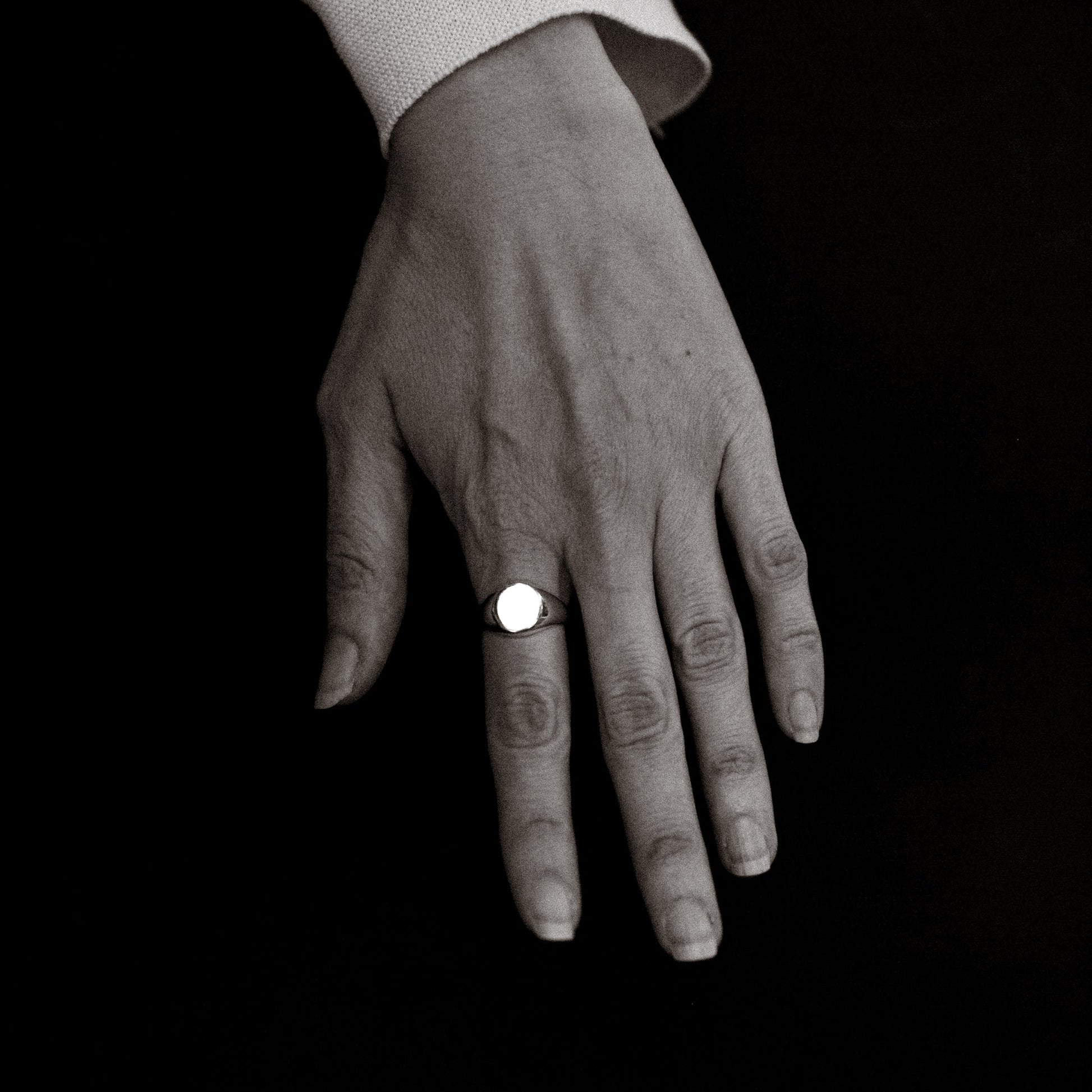 Hand wearing a ring on a black background