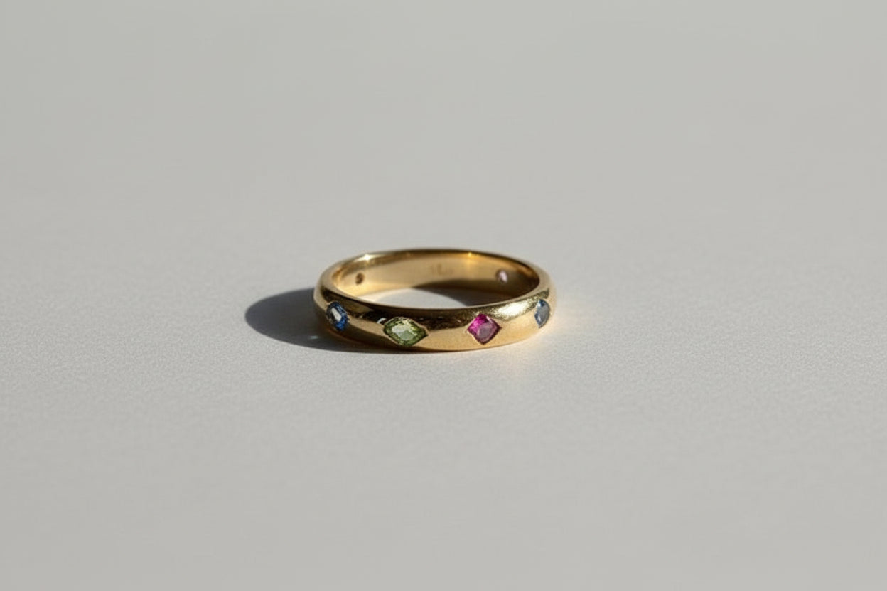 Gold ring with embedded gemstones on a grey studio background